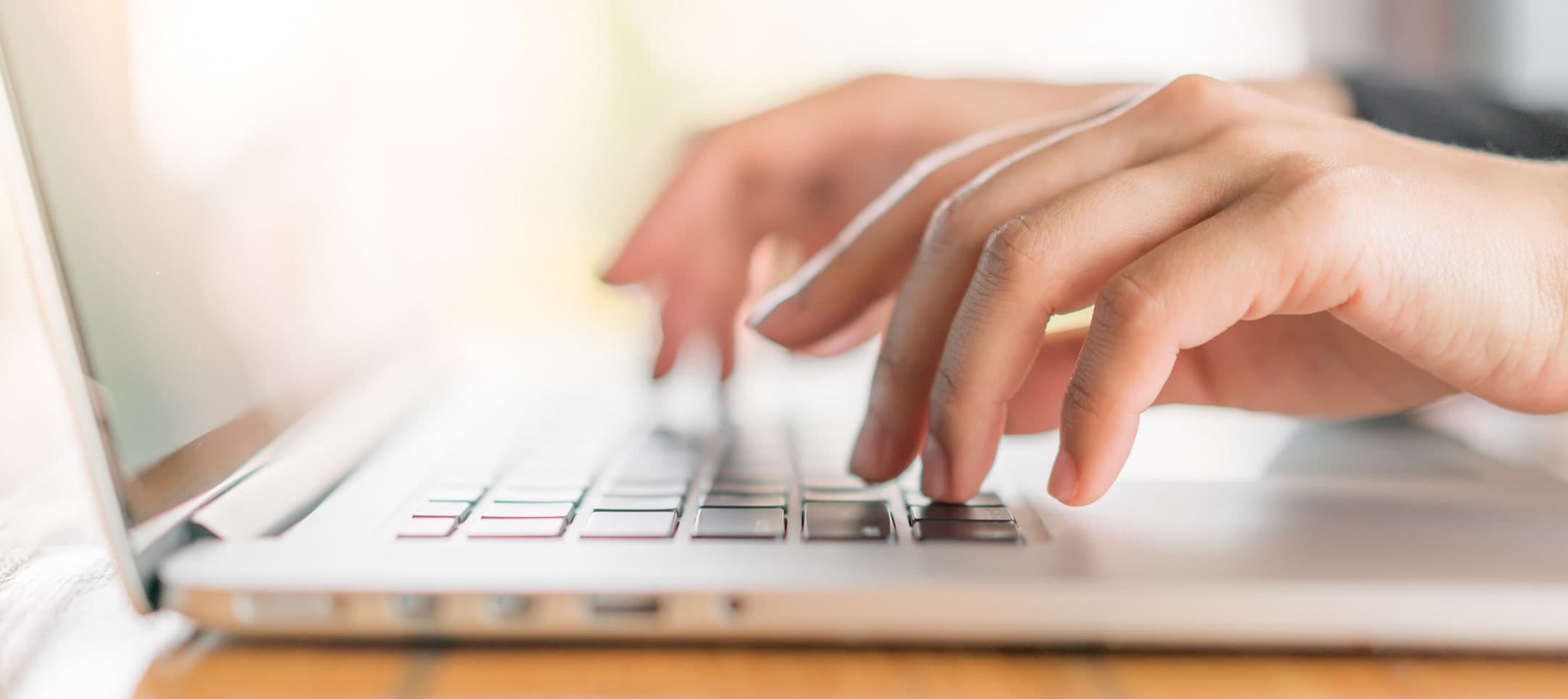 Hands typing on a laptop keyboard